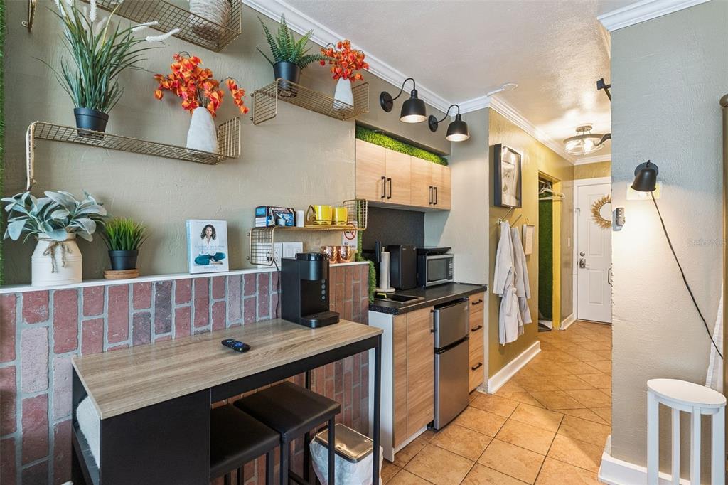 A kitchenette area features a brick-accented breakfast bar, wood-look cabinets, and open wall shelving — 1233 S ATLANTIC AVENUE UNIT 3140, DAYTONA BEACH, FL