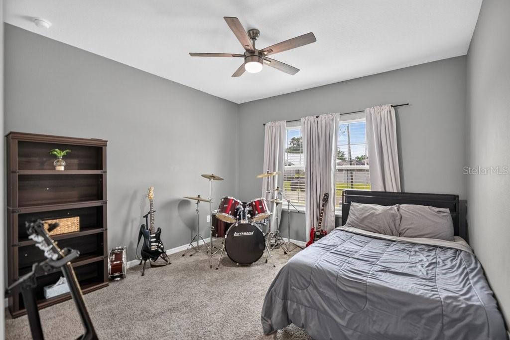 A bedroom with gray walls, carpeted flooring, a bed, and a drum set — 14 WOODWORTH DRIVE, PALM COAST, FL