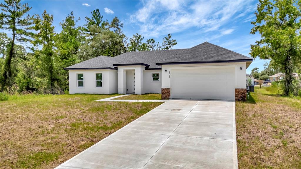 A single-story white house with a two-car garage and a concrete driveway — 6168 SW 154TH STREET, OCALA, FL