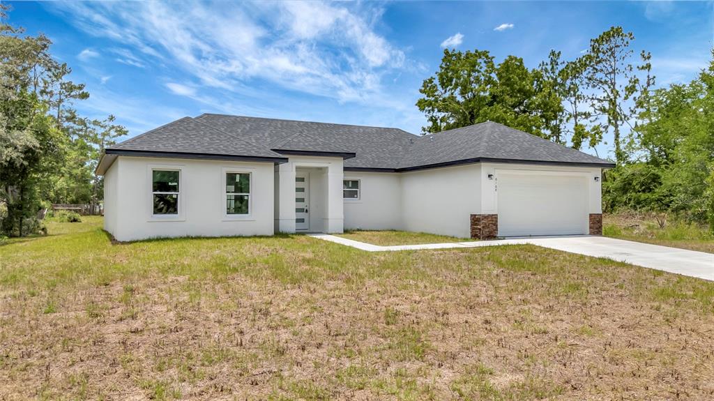 A single-story house with white stucco walls, a dark shingled roof, and a two-car garage — 6168 SW 154TH STREET, OCALA, FL