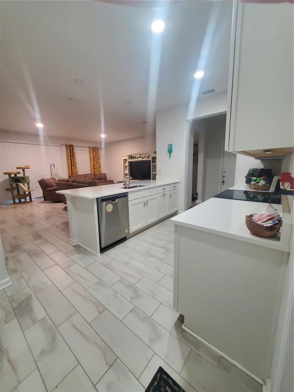 A kitchen with white cabinets and a large island overlooks an open-concept living room — 10960 BRIGHTLEAF COURT, RIVERVIEW, FL