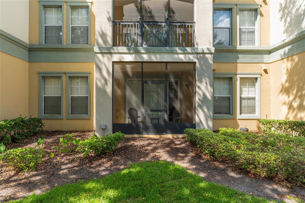 A two-story apartment building exterior featuring a ground-floor screened patio and upper-level balcony — 8180 BOAT HOOK LOOP UNIT 109, WINDERMERE, FL
