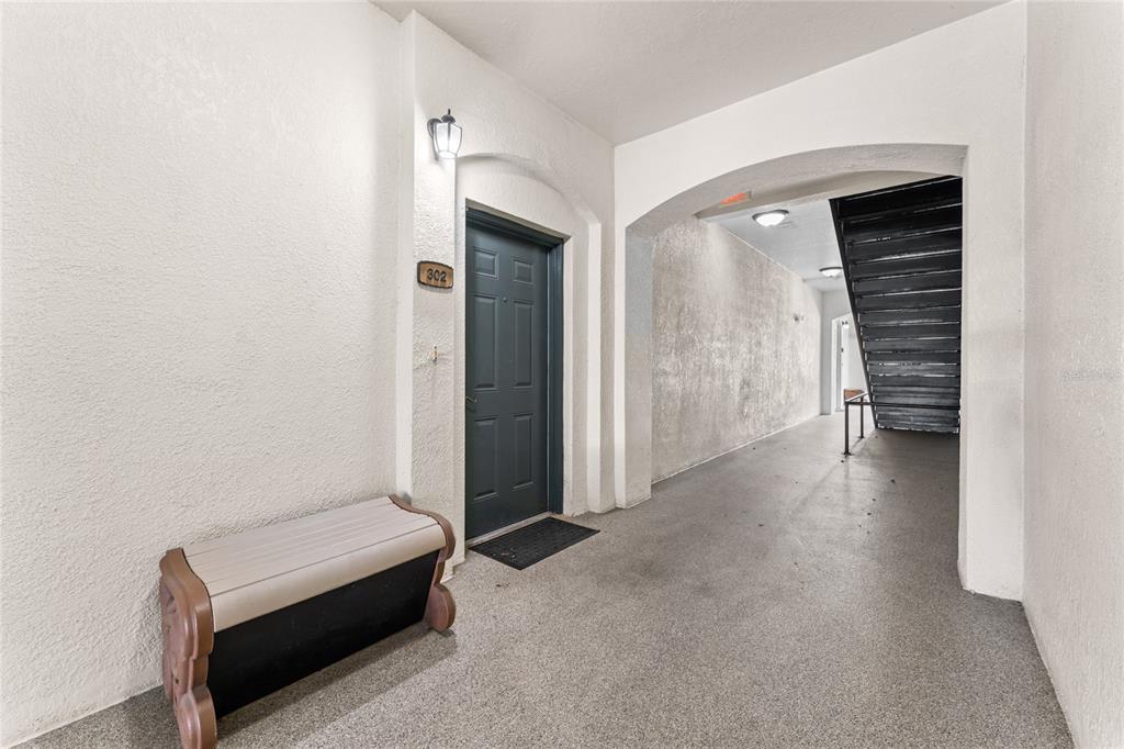 An apartment hallway features a dark door numbered 302, a bench, and a nearby staircase — 8180 BOAT HOOK LOOP UNIT 109, WINDERMERE, FL