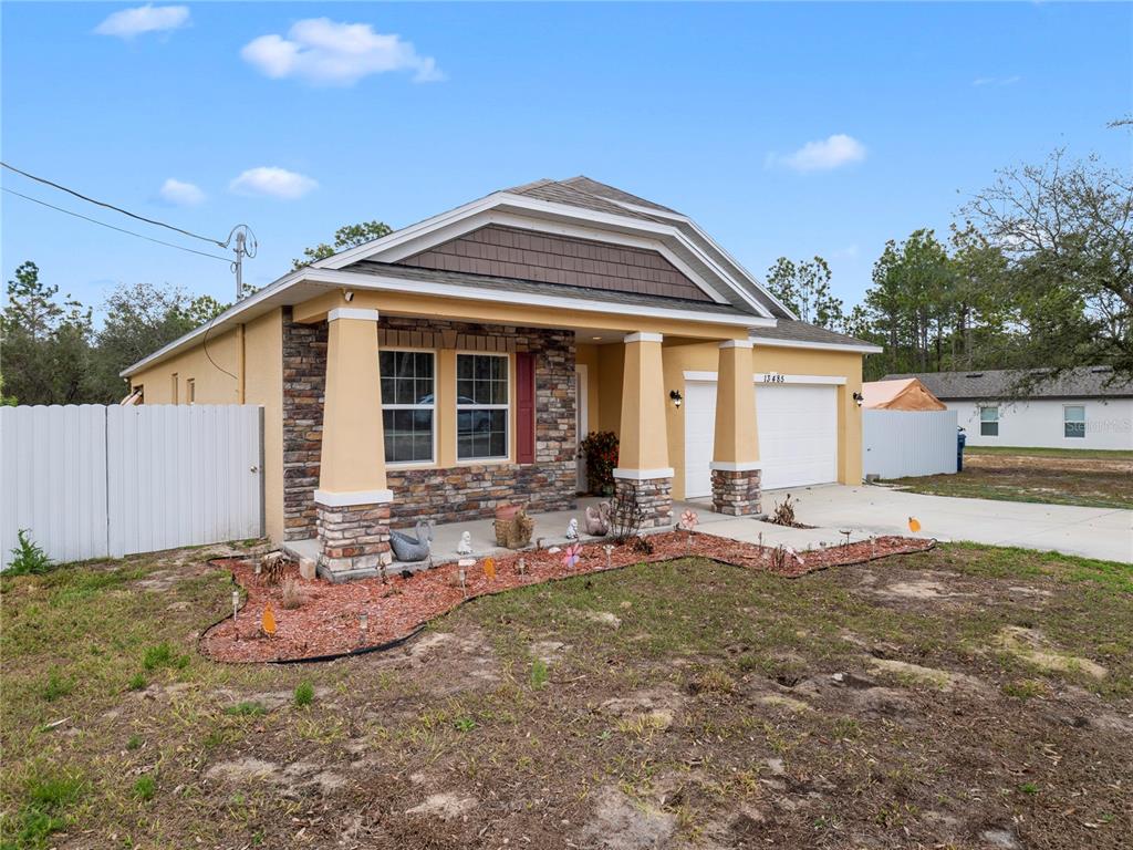 A single-story house with a stone facade, tan stucco, and a front porch — 13485 RESORT AVENUE, BROOKSVILLE, FL