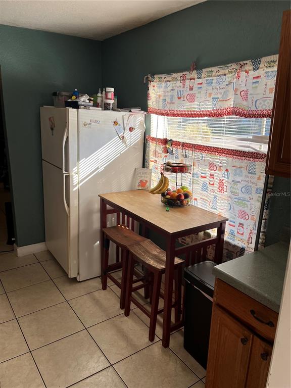 A kitchen features a white refrigerator, a wooden dining table with stools, and patterned curtains — 4325 LAKE LAWNE AVENUE, ORLANDO, FL