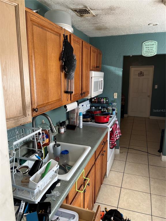 A kitchen features wooden cabinets, a white sink, a stove, and teal-colored walls — 4325 LAKE LAWNE AVENUE, ORLANDO, FL