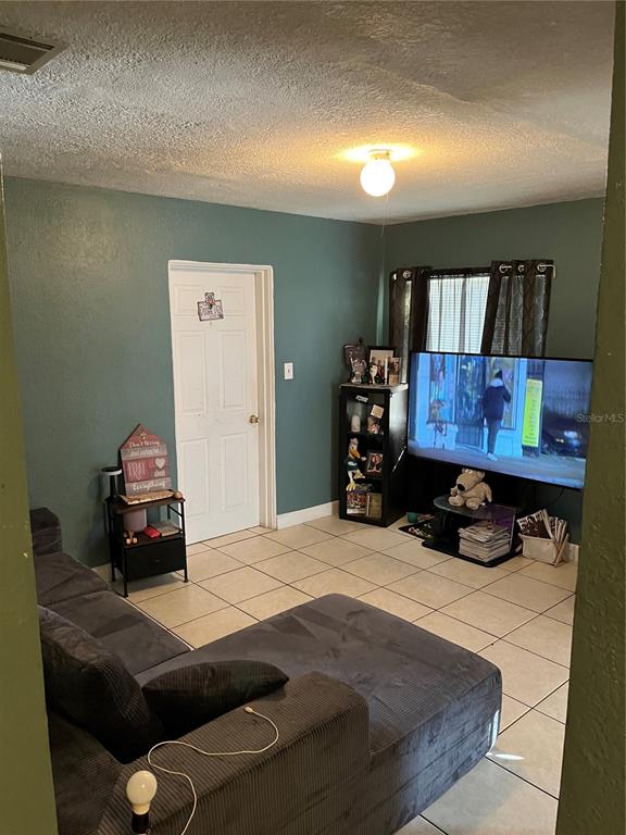 A living room features a grey sectional sofa, tiled floors, teal walls, and a television — 4325 LAKE LAWNE AVENUE, ORLANDO, FL