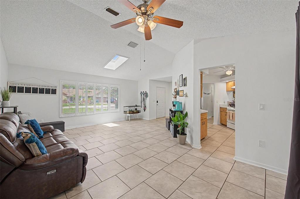 A living room with tile floors, a vaulted ceiling, a ceiling fan, and a skylight — 2028 NOBLETON AVENUE, SPRING HILL, FL