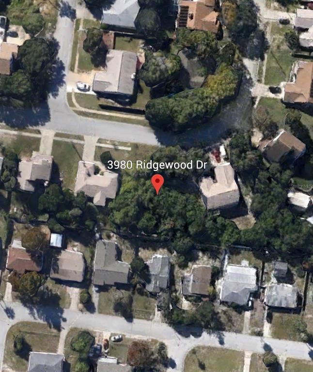 This aerial view shows a wooded residential lot surrounded by houses in a suburban neighborhood — 3980 RIDGEWOOD DRIVE, TITUSVILLE, FL