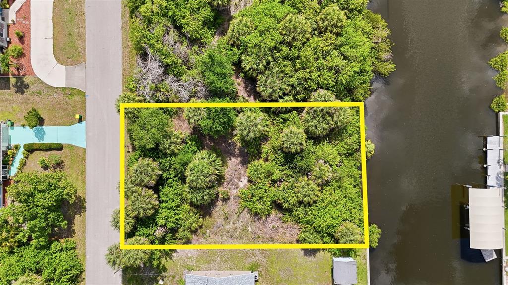 An aerial view shows a rectangular, tree-covered vacant lot situated between a road and canal — 18318 VAN NUYS CIRCLE, PORT CHARLOTTE, FL