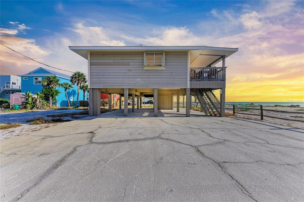 An elevated house with a concrete driveway and a wooden deck overlooking the ocean — 45 WILHELM DRIVE, ENGLEWOOD, FL