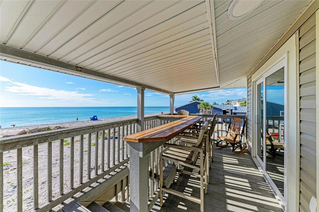 A covered wooden deck overlooks the beach with a bar-style counter and outdoor seating — 45 WILHELM DRIVE, ENGLEWOOD, FL
