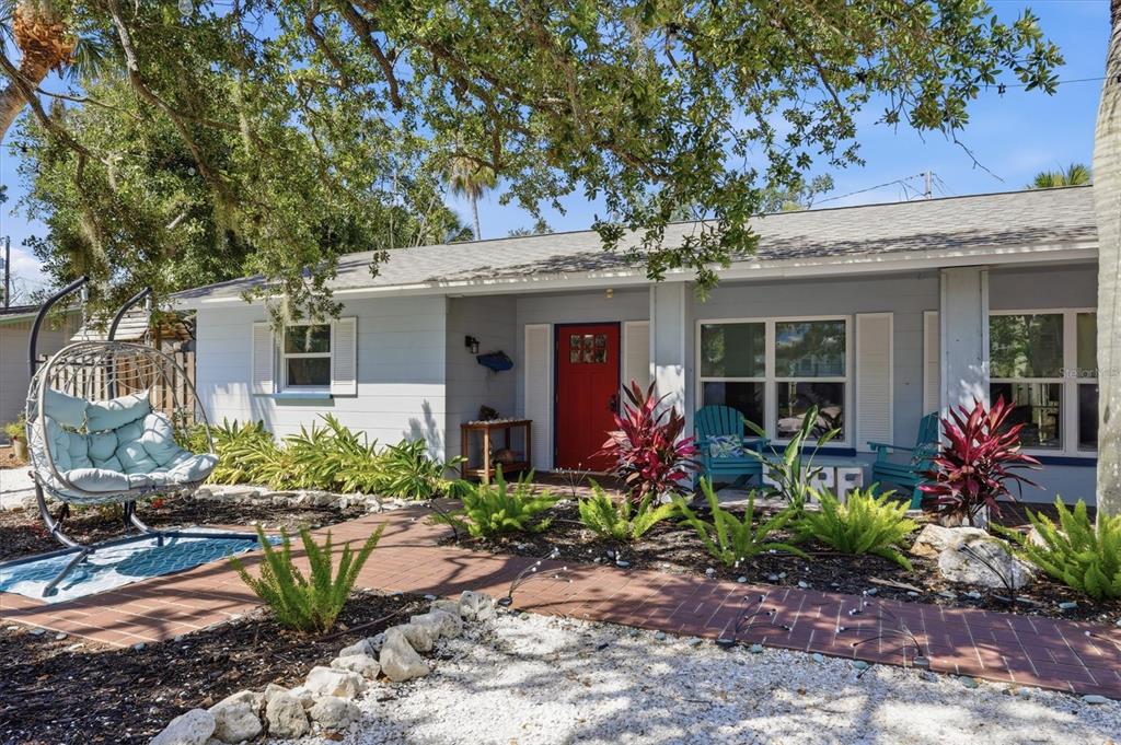 A light blue single-story house features a red front door and a brick walkway — 5128 OXFORD DRIVE, SARASOTA, FL