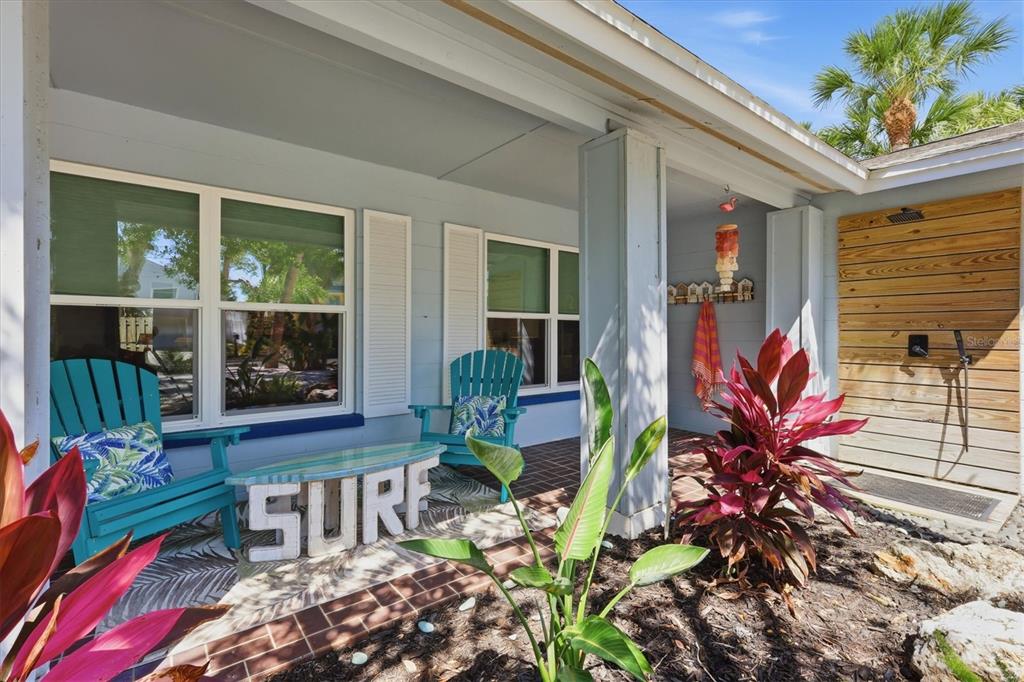 A front porch features two teal Adirondack chairs, a surf sign, and an outdoor shower — 5128 OXFORD DRIVE, SARASOTA, FL