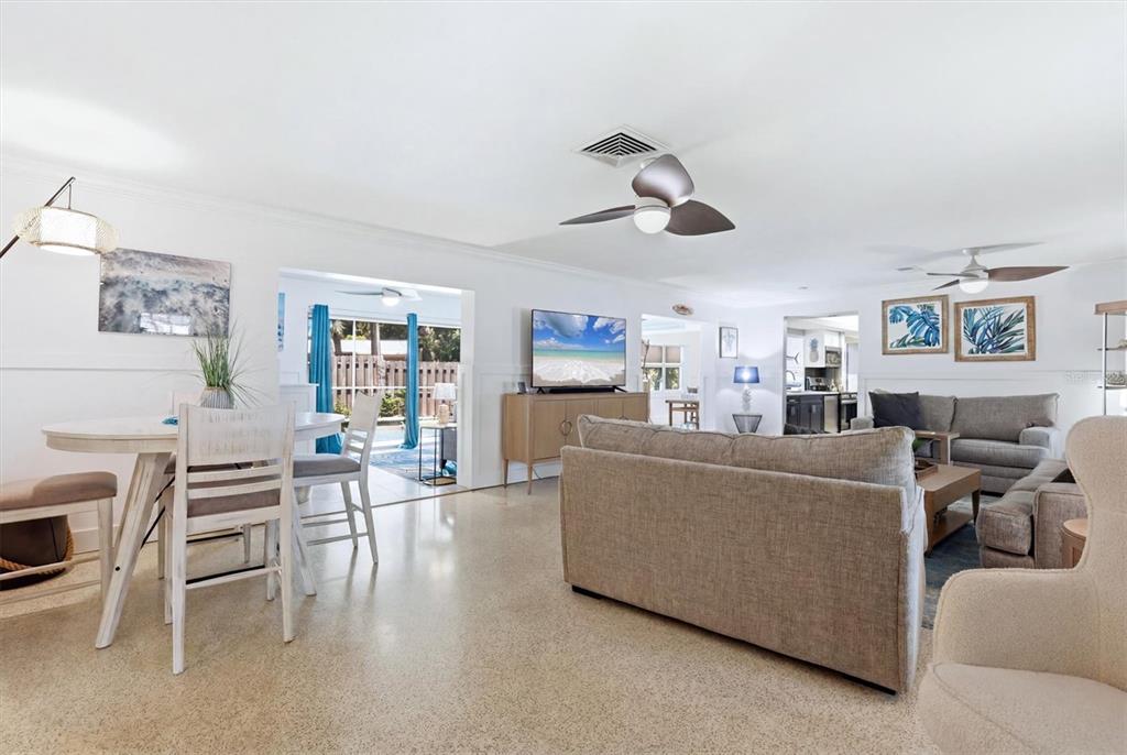 An open-concept living and dining area features light-colored flooring, a ceiling fan, and neutral furniture — 5128 OXFORD DRIVE, SARASOTA, FL