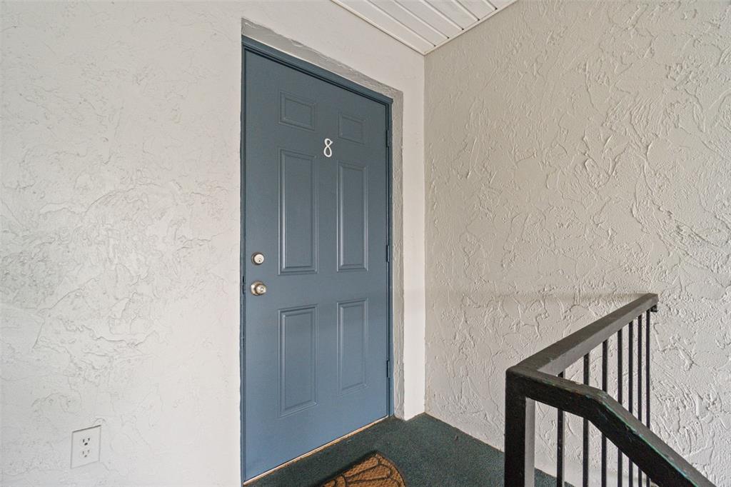 A blue front door marked with the number eight sits at the top of a staircase — 1036 PLANTATION DRIVE UNIT D8, KISSIMMEE, FL