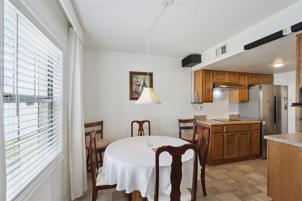 A dining area with a round table and wooden chairs sits adjacent to a kitchen — 1036 PLANTATION DRIVE UNIT D8, KISSIMMEE, FL