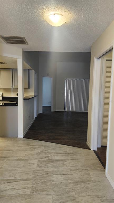 An interior view shows a kitchen with a breakfast bar transitioning to a living area — 7413 MEAD DRIVE, SPRING HILL, FL