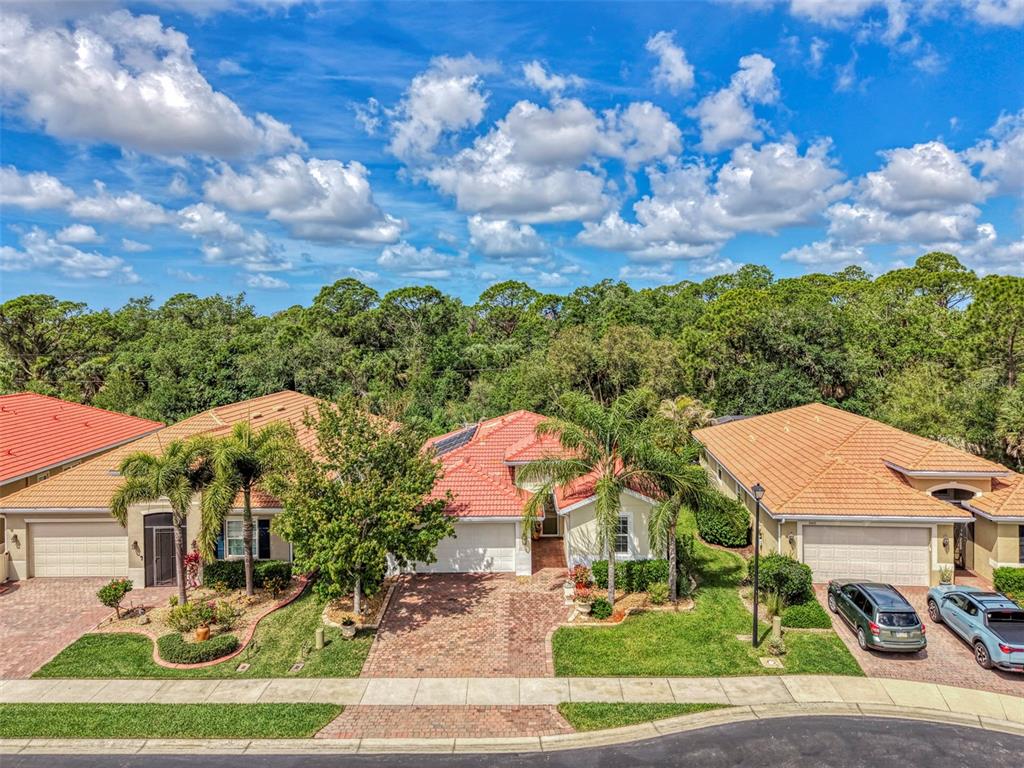 An aerial view shows three suburban houses with orange tile roofs and brick driveways — 11455 BLACKFIN STREET, VENICE, FL
