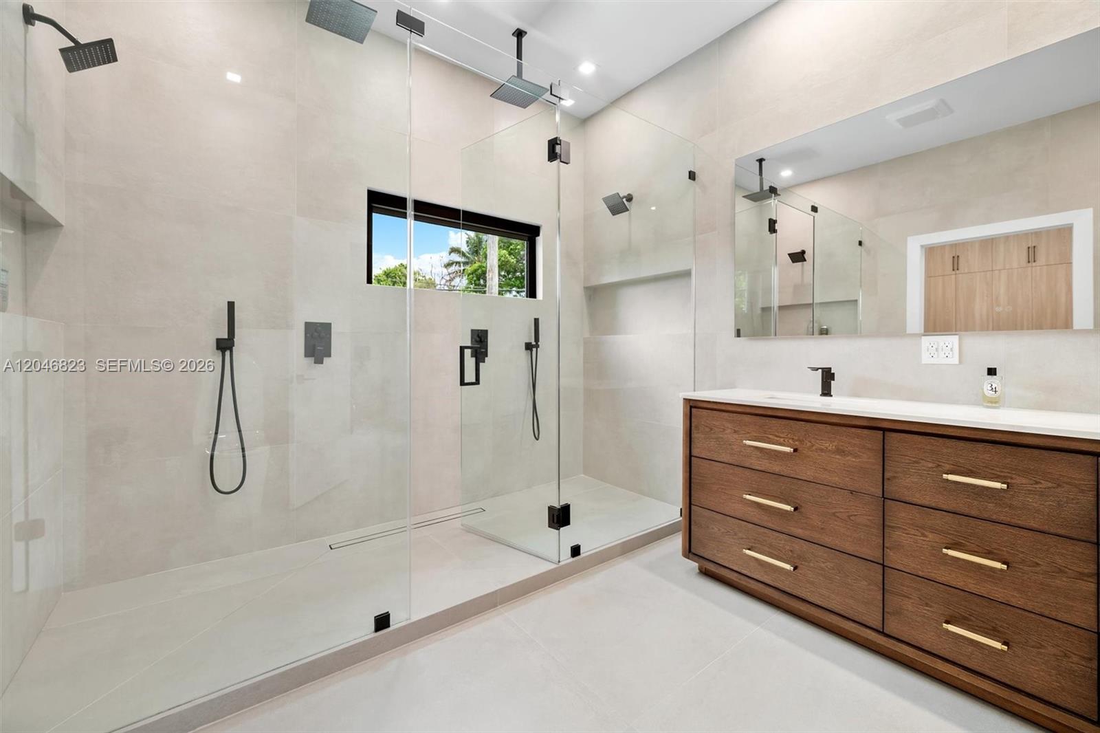 A modern bathroom features a large glass-enclosed walk-in shower and a wooden double vanity — 95 NW 52nd St, Miami FL 33127, MIAMI, FL