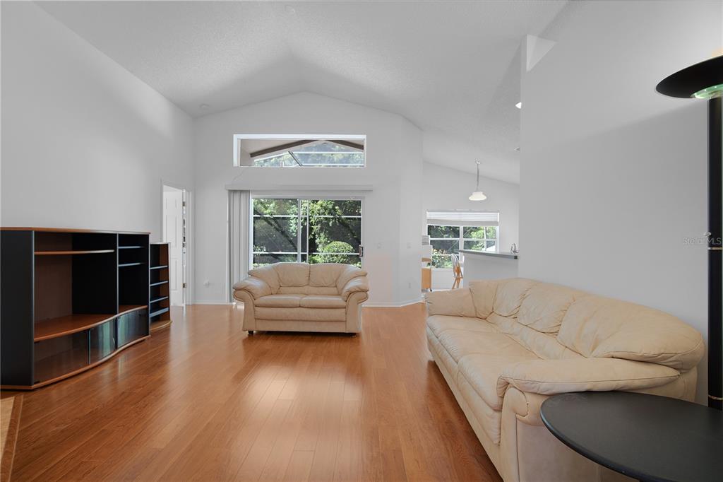 A living room features hardwood floors, vaulted ceilings, two beige sofas, and a media console — 839 MATTOCKS COURT, CASSELBERRY, FL