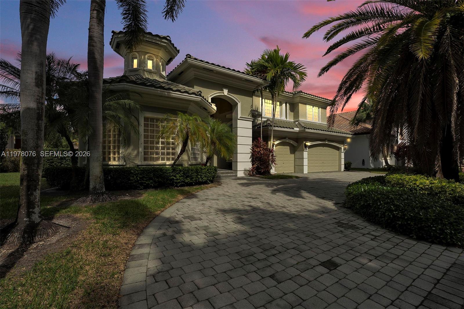 A two-story house with a paved driveway, palm trees, and a turret at dusk — 10221 Blue Palm St, Plantation FL 33324, PLANTATION, FL