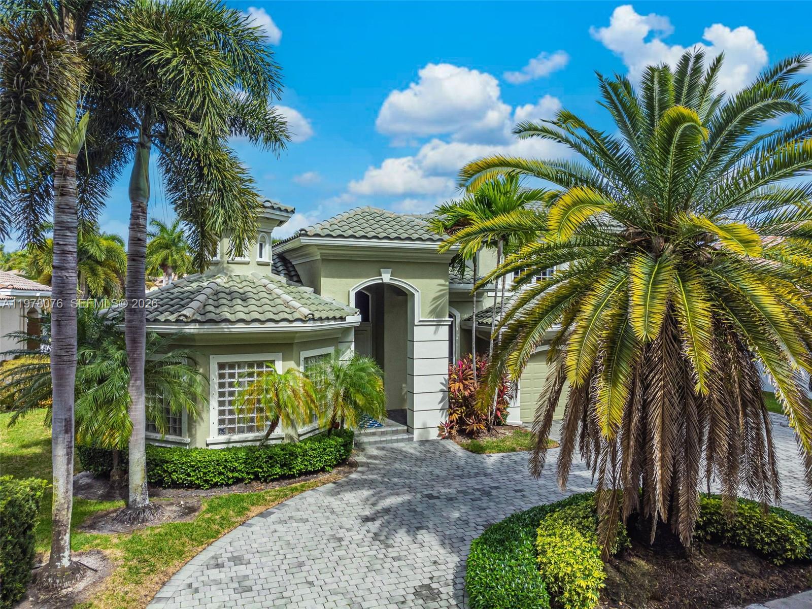 A light green house with a tiled roof and a paved driveway surrounded by palm trees — 10221 Blue Palm St, Plantation FL 33324, PLANTATION, FL