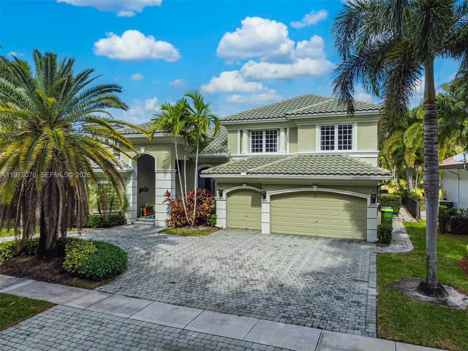 A two-story house with a paved driveway, a three-car garage, and palm trees — 10221 Blue Palm St, Plantation FL 33324, PLANTATION, FL