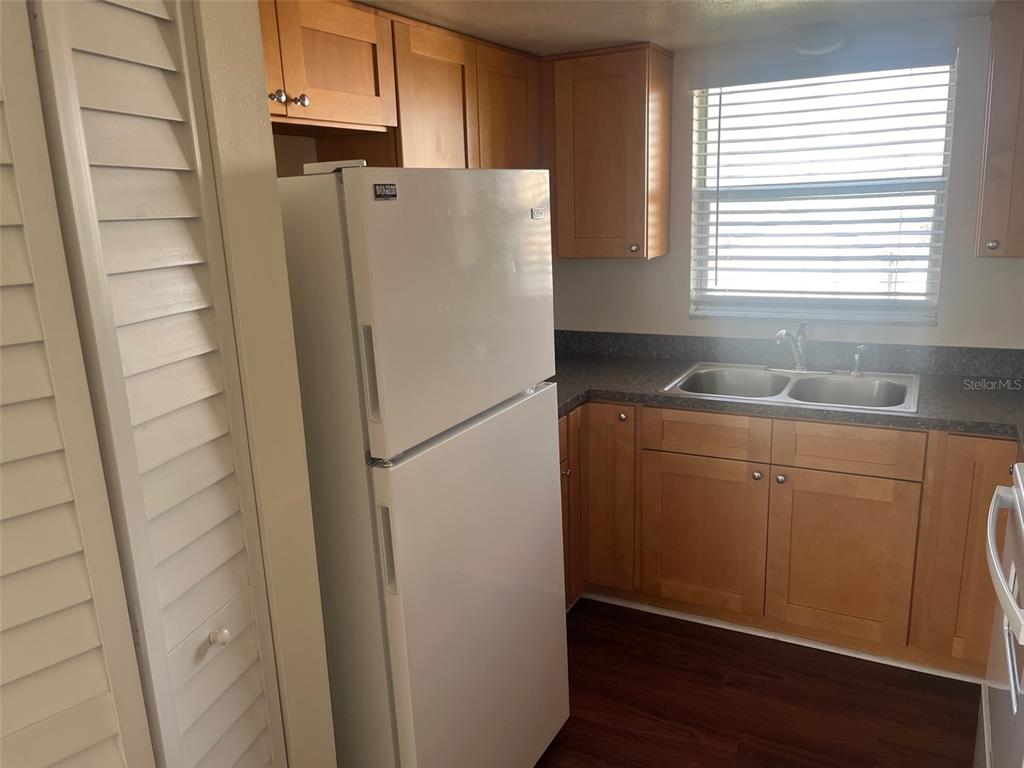 A kitchen features light wood cabinets, a white refrigerator, and a double-basin sink — 105 11TH AVENUE UNIT 10, ST PETE BEACH, FL