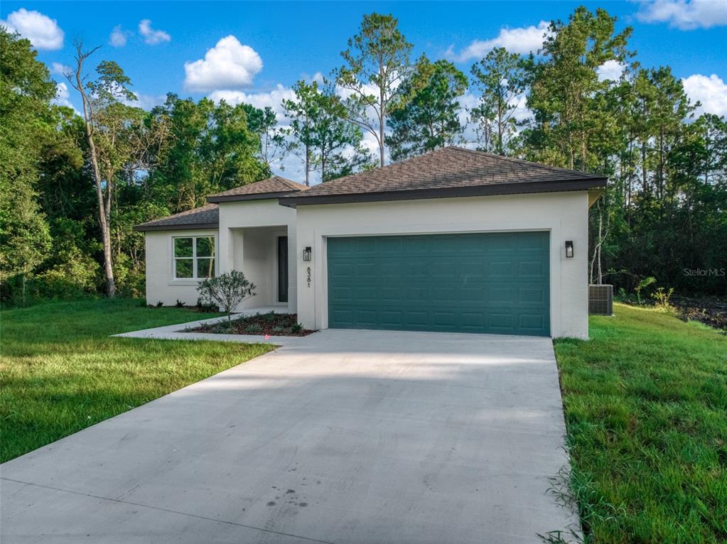 A single-story house with a teal garage door, white stucco exterior, and a concrete driveway — 8381 MANTUA AVENUE, SEBRING, FL
