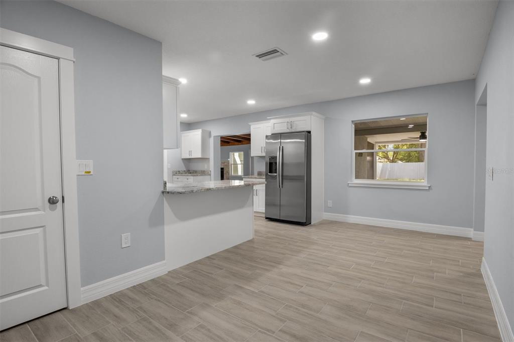 A kitchen with light gray walls, white cabinets, stainless steel appliances, and wood-look tile flooring — 3945 CHART PRINE ROAD, LAKELAND, FL