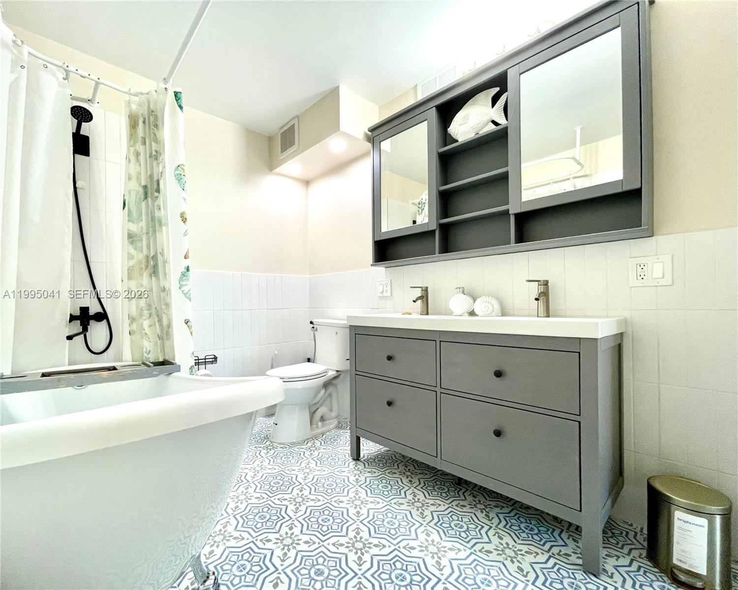 A bathroom features a gray double vanity, a freestanding tub, and patterned floor tiles — 1913 S OCEAN DR # 129, Hallandale Beach FL 33009, HALLANDALE BEACH, FL