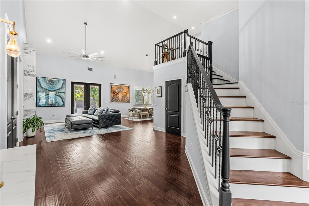 A living room with dark wood floors, a staircase with black railings, and a dining area — 1840 BRYAN AVENUE, WINTER PARK, FL