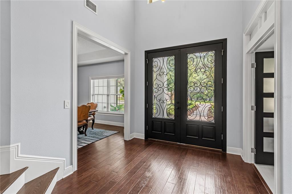 An entryway with dark wood floors, a black double front door, and an adjacent dining room — 1840 BRYAN AVENUE, WINTER PARK, FL