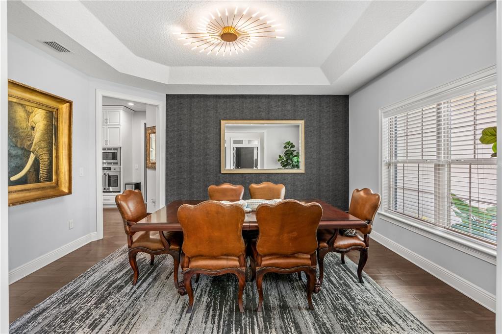 A dining room features a dark accent wall, leather chairs, and a modern sunburst chandelier — 1840 BRYAN AVENUE, WINTER PARK, FL