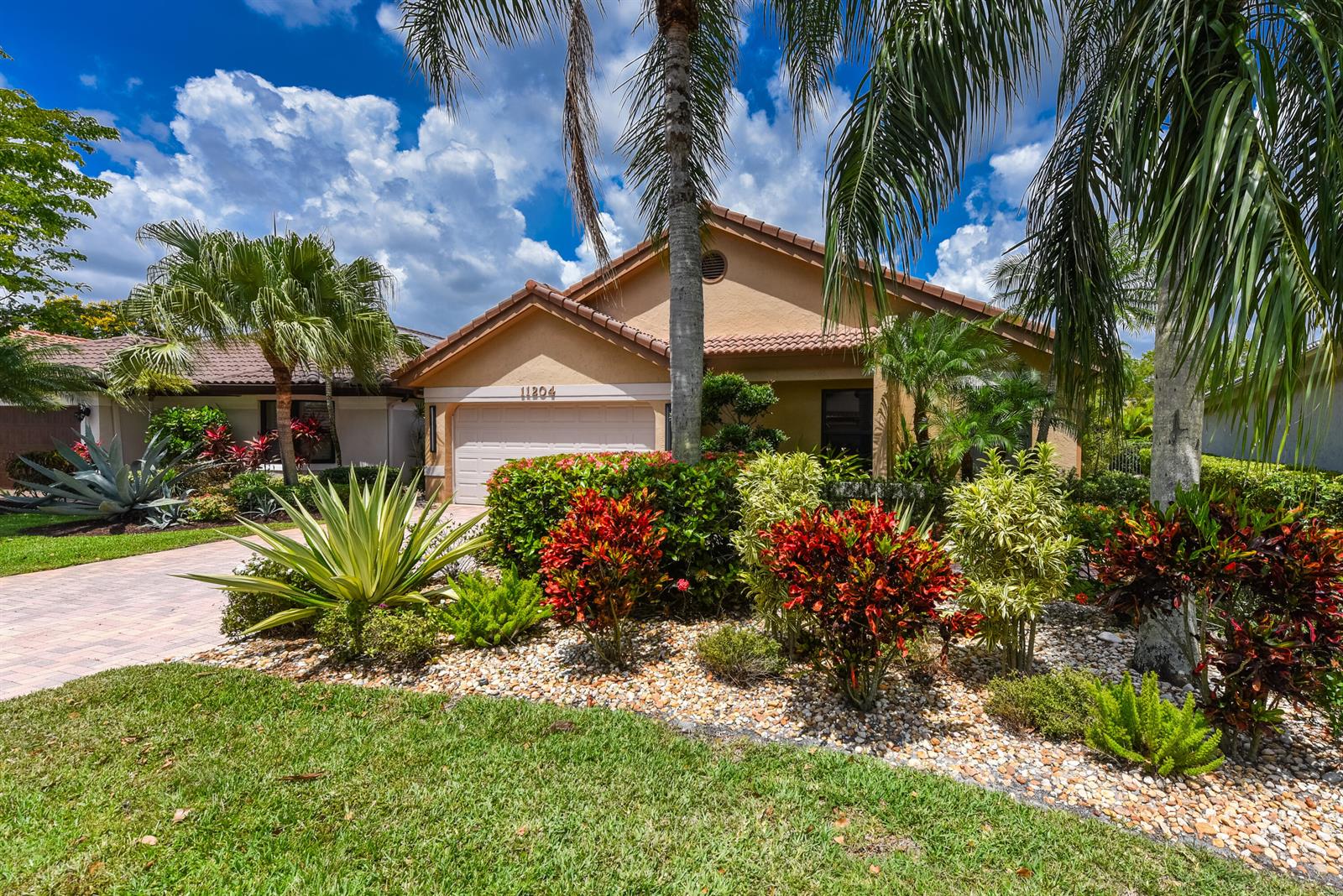 A single-story house with a beige stucco exterior, a tiled roof, and landscaped front yard — 11204 Cloverleaf Circle, Boca Raton FL 33428, BOCA RATON, FL