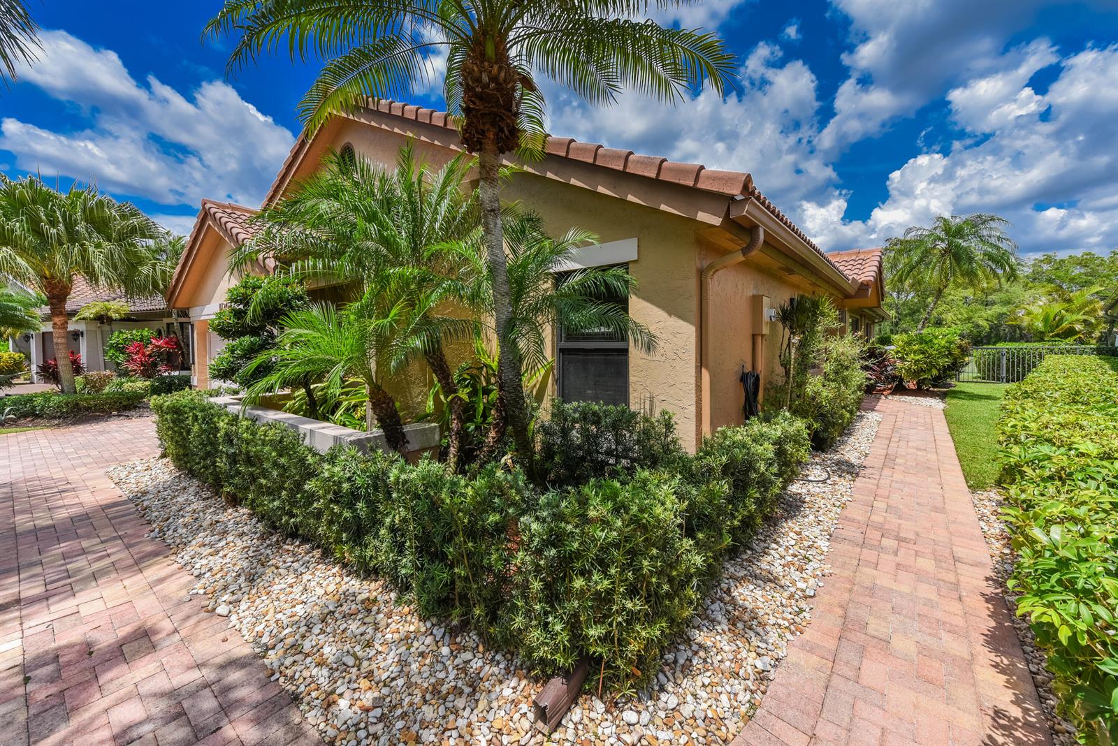 A tan stucco house with a tiled roof features a brick walkway and palm trees — 11204 Cloverleaf Circle, Boca Raton FL 33428, BOCA RATON, FL