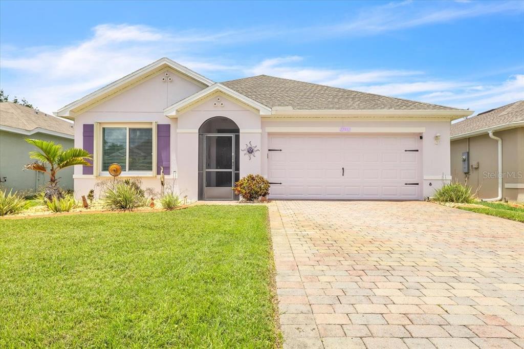 A single-story house with a light pink exterior, purple shutters, and a paved driveway — 27932 ARROWHEAD CIRCLE, PUNTA GORDA, FL