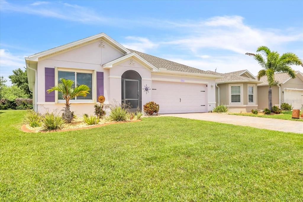 A light pink single-story house features a two-car garage, purple shutters, and a palm tree — 27932 ARROWHEAD CIRCLE, PUNTA GORDA, FL