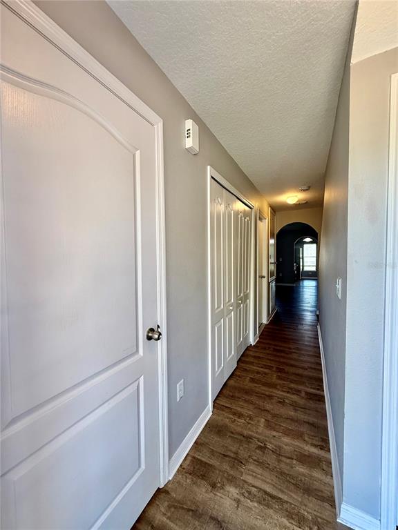 A hallway with wood-look flooring, white doors, and a closet with bifold doors — 4505 ASHBURN SQUARE DRIVE, TAMPA, FL