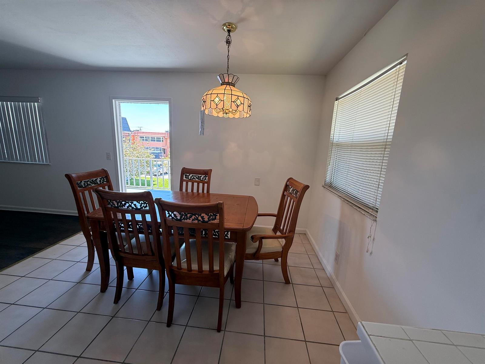 A dining room with a wooden table, four chairs, a pendant light, and tile flooring — 516 Saxony K, Delray Beach FL 33446, DELRAY BEACH, FL