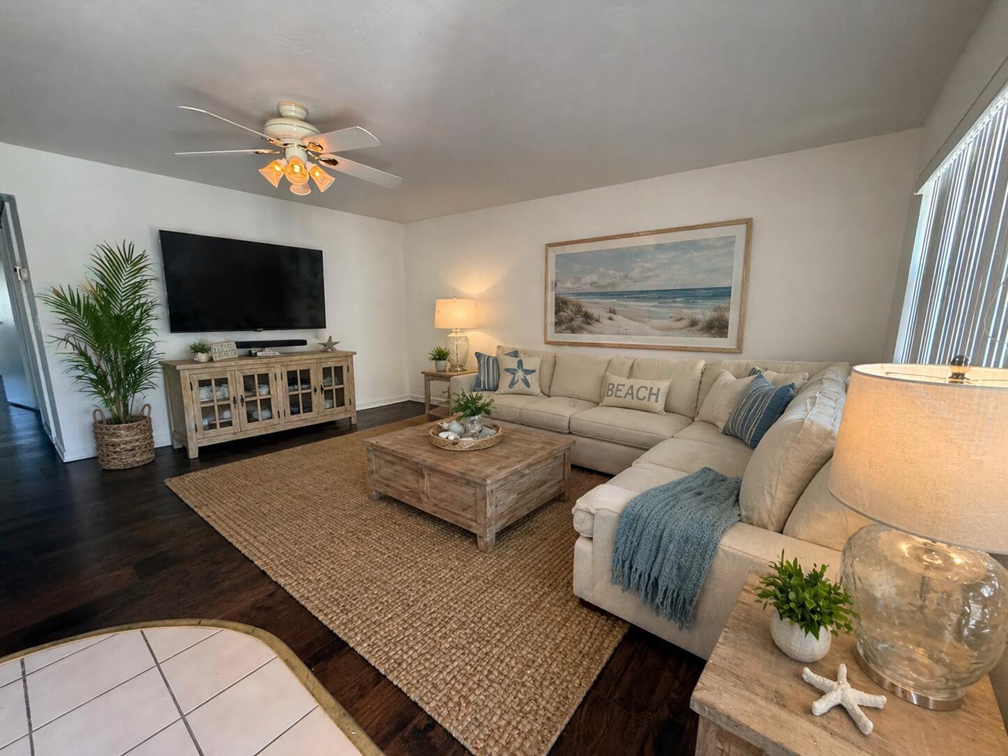A living room features a sectional sofa, wooden coffee table, television, and coastal-themed decor — 516 Saxony K, Delray Beach FL 33446, DELRAY BEACH, FL