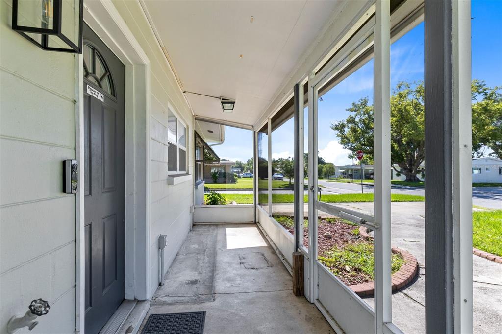 A screened-in porch with a concrete floor, a gray front door, and white siding — 1805 VERONA STREET, KISSIMMEE, FL