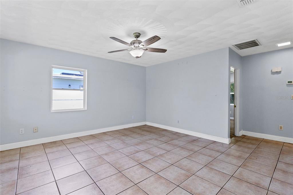 An empty room with light blue walls, tile flooring, and a ceiling fan — 1805 VERONA STREET, KISSIMMEE, FL