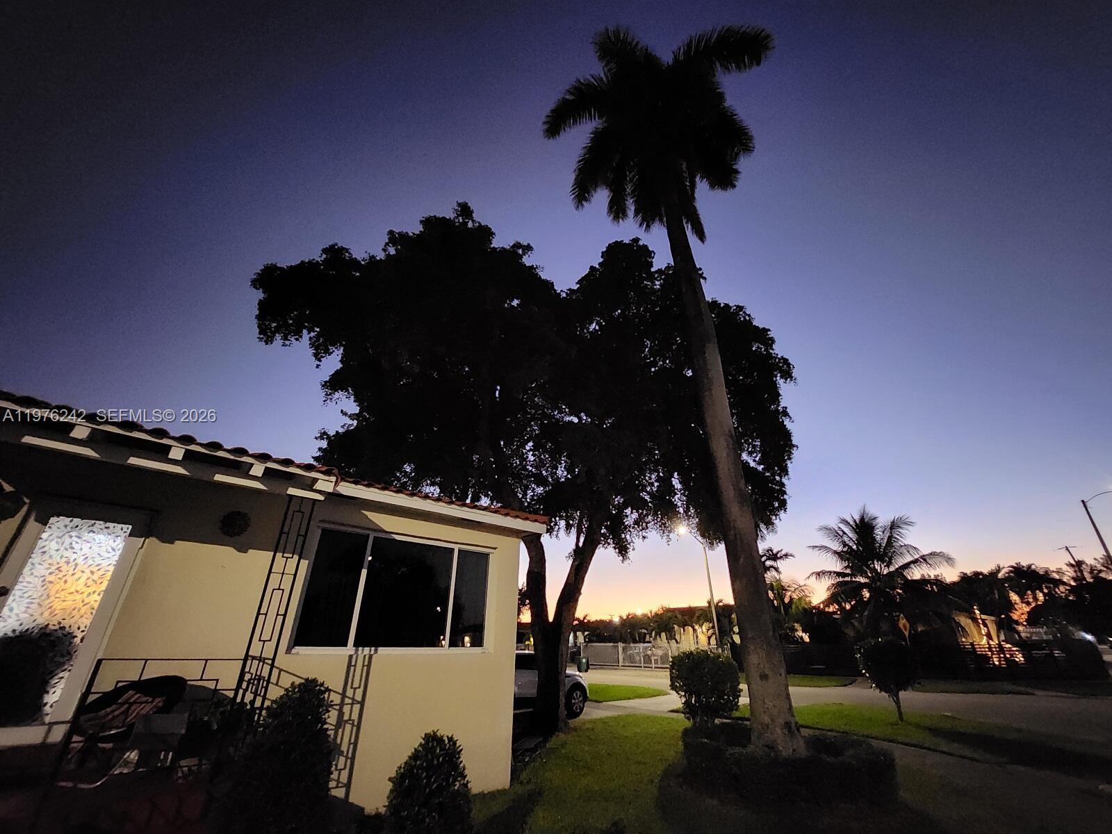 A palm tree and a large tree stand beside a house at twilight — 3560 NW 19th St, Miami FL 33125, MIAMI, FL
