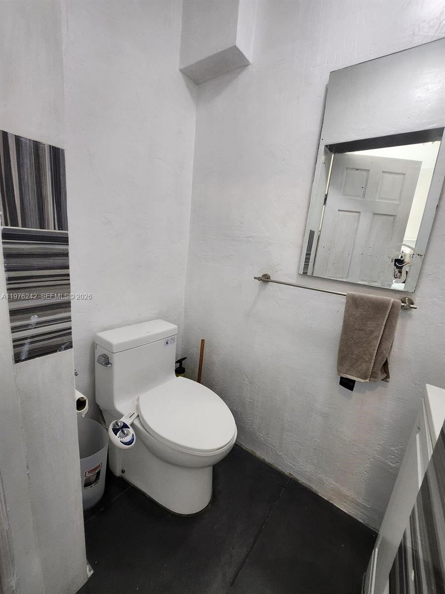 A small bathroom features a white toilet with a bidet attachment and a wall mirror — 3560 NW 19th St, Miami FL 33125, MIAMI, FL