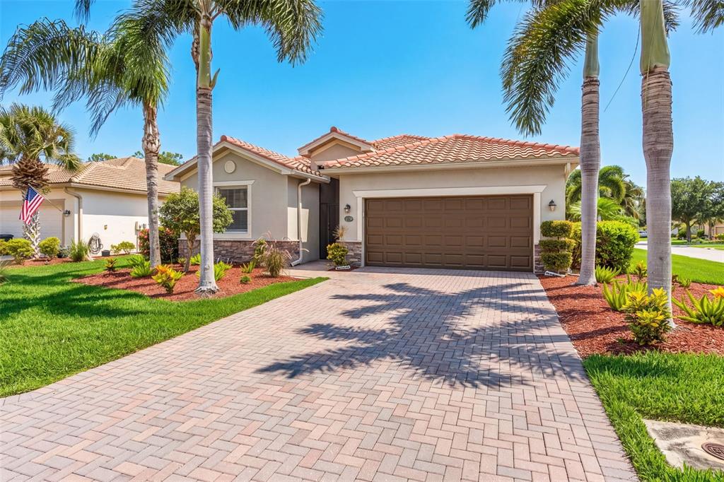 A single-story house with a tiled roof, brown garage door, and a brick paver driveway — 21250 BELLA TERRA BOULEVARD, ESTERO, FL