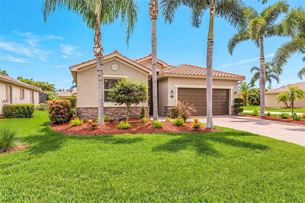 A single-story house with a two-car garage, palm trees, and a landscaped front yard — 21250 BELLA TERRA BOULEVARD, ESTERO, FL