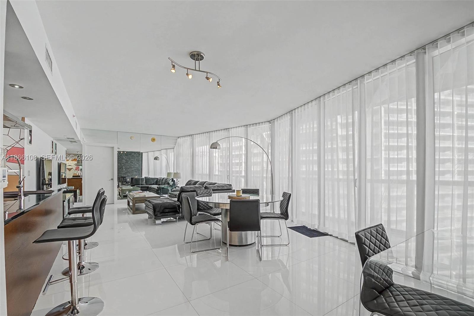 A modern open-concept living and dining area features white tile floors and floor-to-ceiling curtains — 495 Brickell Ave # 3504, Miami FL 33131, MIAMI, FL