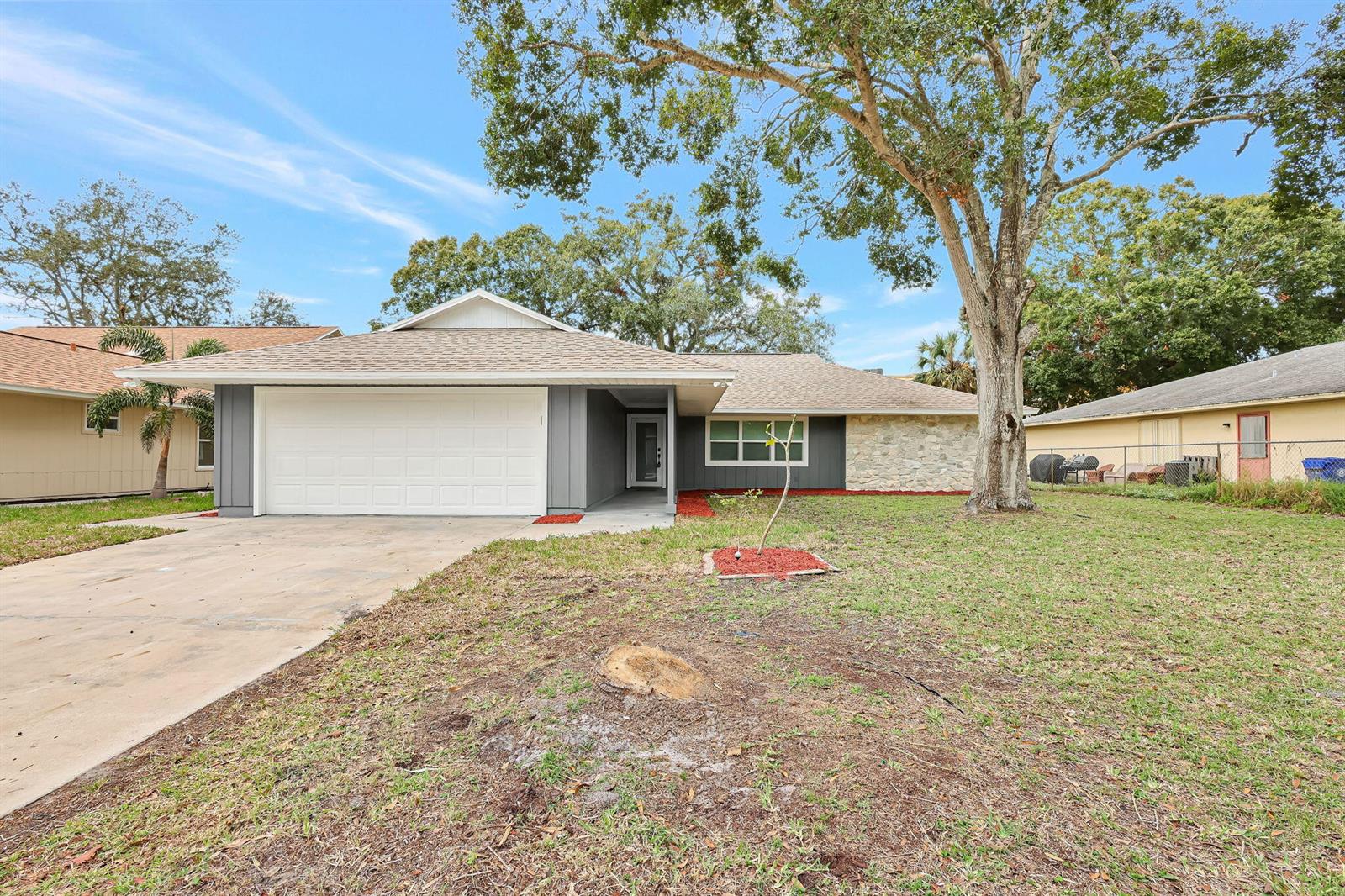 A single-story house with a gray exterior, stone facade, and a two-car garage — 1825 39th Avenue, Vero Beach FL 32960, VERO BEACH, FL